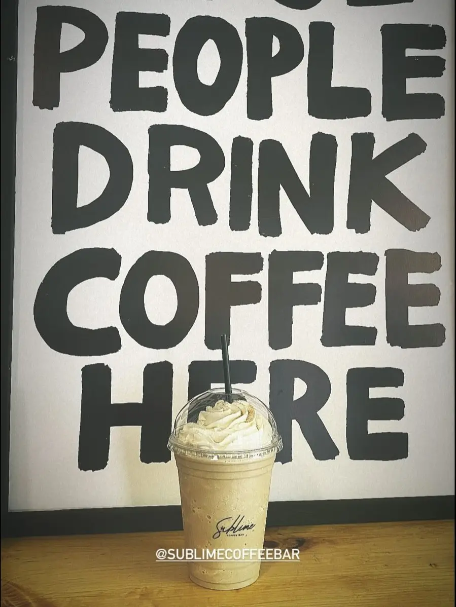 Un frappé con crema y el vaso de Sublime frente a su cuadro COOL PEOPLE DRINK COFFEE HERE